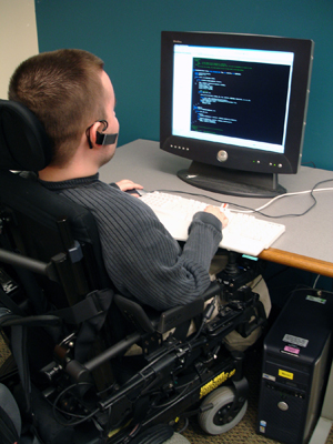 A pair of students interact as one student types on a computer.